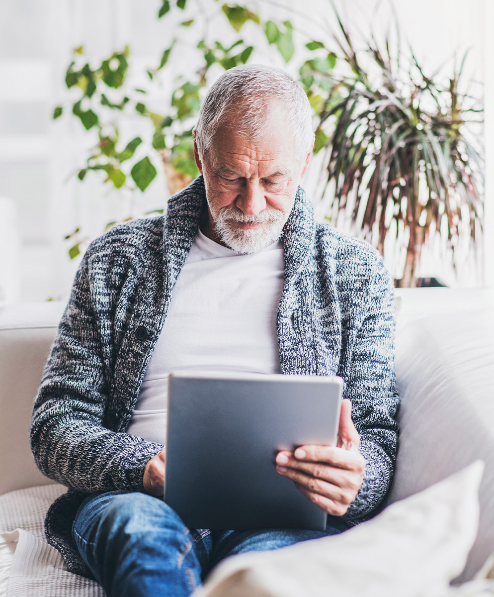 senior man on couch reading tablet fixed index annuity rates lifelong financial solutions